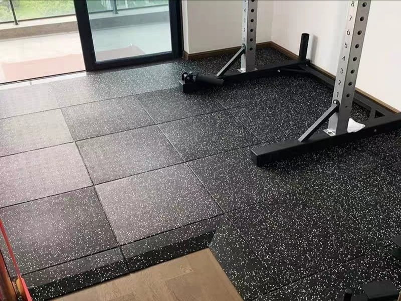 A photo showing the process of cutting a rubber gym tile with a utility knife and straight edge.